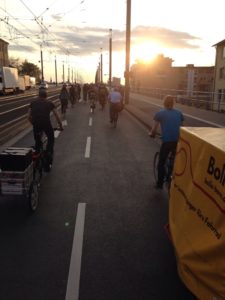 Die Critical Mass mit Fahrradanhängern fährt über die Kennedy Brücke dem Sonnenuntergang entgegen.