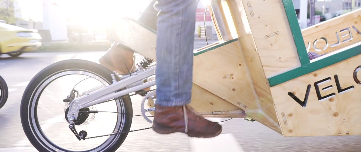Velowerft-Lastenrad auf der Straße aus Holz von der Seite mit der Sonne im Hintergrund