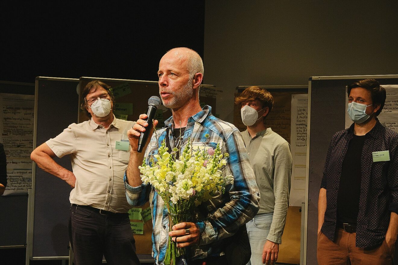 Guido Preuß von der Brotfabrik Bonn mit Blumenstrauß und Mikrofon