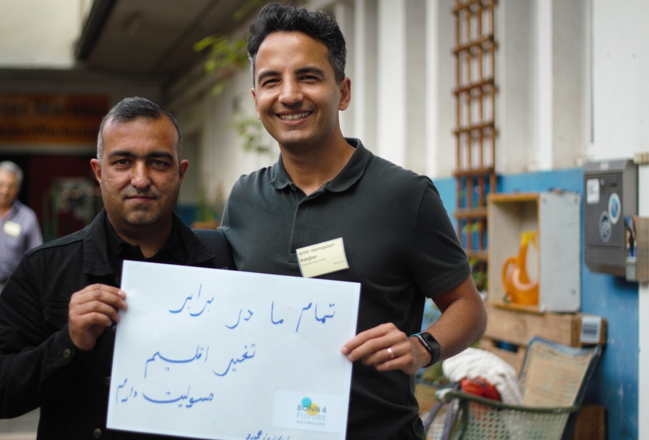 2 männliche Personen mit Schild in persischer Schrift