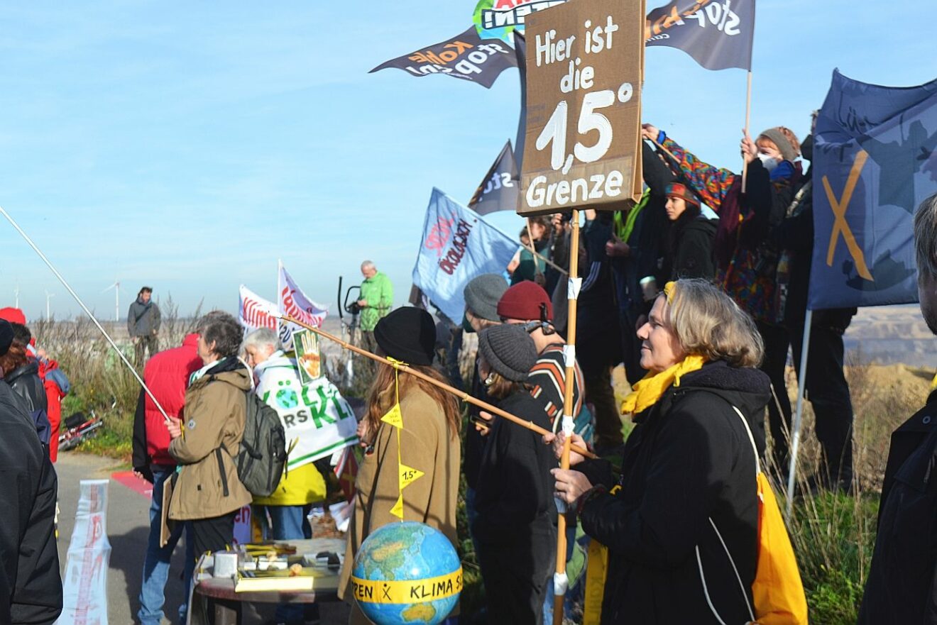 Demonstrantin in Lützeratz mit Pappschild: Hier ist die 1,5 Grad Grenze