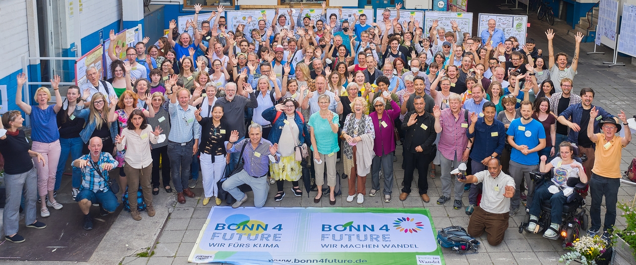 Über 100 Bürger:innen winken freudig in die Kamera. Vor Ihnen das Bonn4Future Banner- Foto;Christoph Schnüll