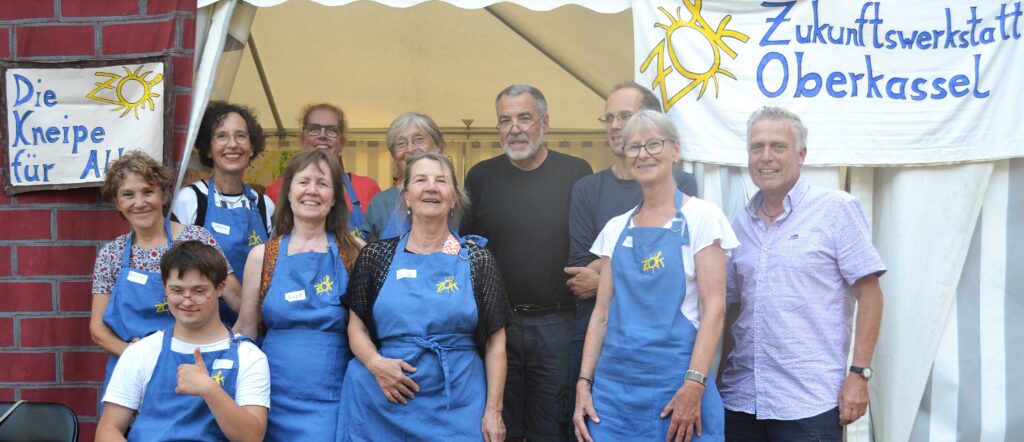 Fröhliche Menschen in blauen Schützen vor dem Eingang der Popup Kneipe im Zelt: Foto Gesa Maschkowski