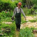 Man mit orangenem Helm und Motorsäge