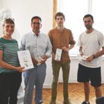 Gesa Maschkowski, Guido Déus, Raphael Räpple und Max Frenken stehen im Büro von Guido Deus und halten Flyer vom Zukunftsprogramm in den Händen und lächeln freundlich in die Kamera