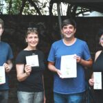 4 Personen im Hof des alten Rathauses halten das Zukunftsprogramm in die Kamera und lächeln