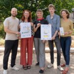 5 Personen stehen unter einem Baum und halten das Zukunftsprogramm und ein Plakat mit allen Unterstützer-Initiativen in die Kamera