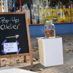 In einem Schaufenster hängen große Zeichnungen, davor steht ein Banner auf dem steht: ZUsammenKÜNFTE
