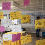 Bunte rosa, gelbe und weiße Kartons mit frühlichen Zeichnungen hängen an Fäden von der Decke, darauf steht zum Beispiel GE-meinsam oder Entschleunigung oder Grüne Essbare Stadt