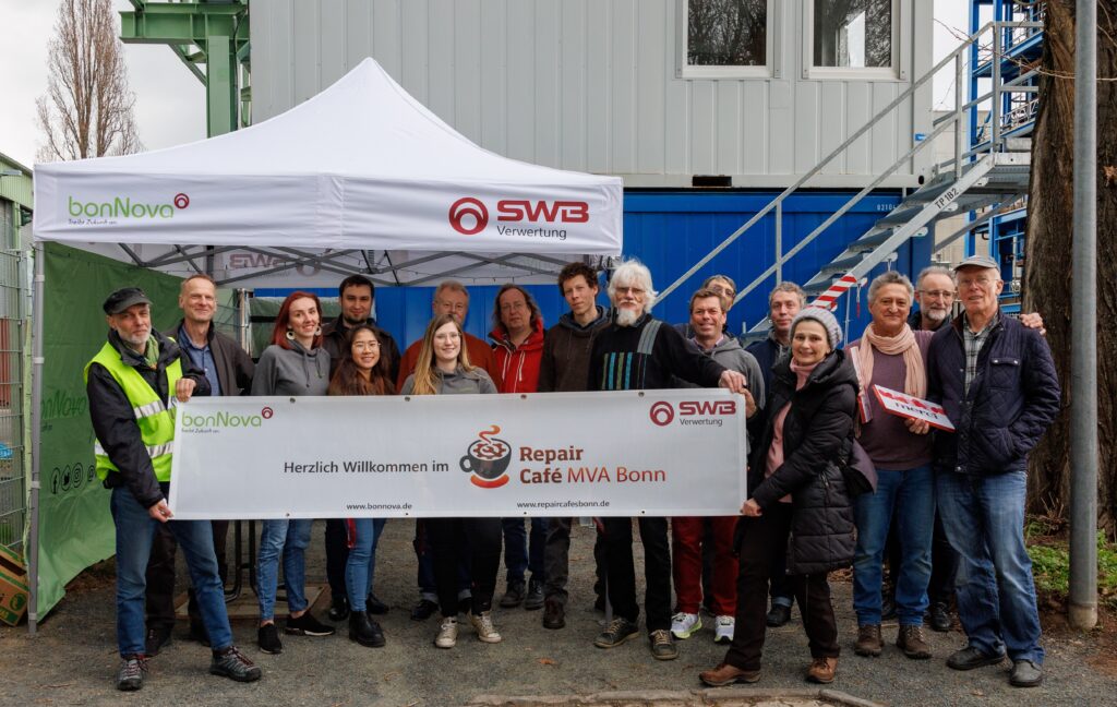 Vertreter und Vertreterinnen des Bonn im Wandel Repaircafes der Stadtwerke und der MVA fröhlich hinter einem Repaircafe Bonner