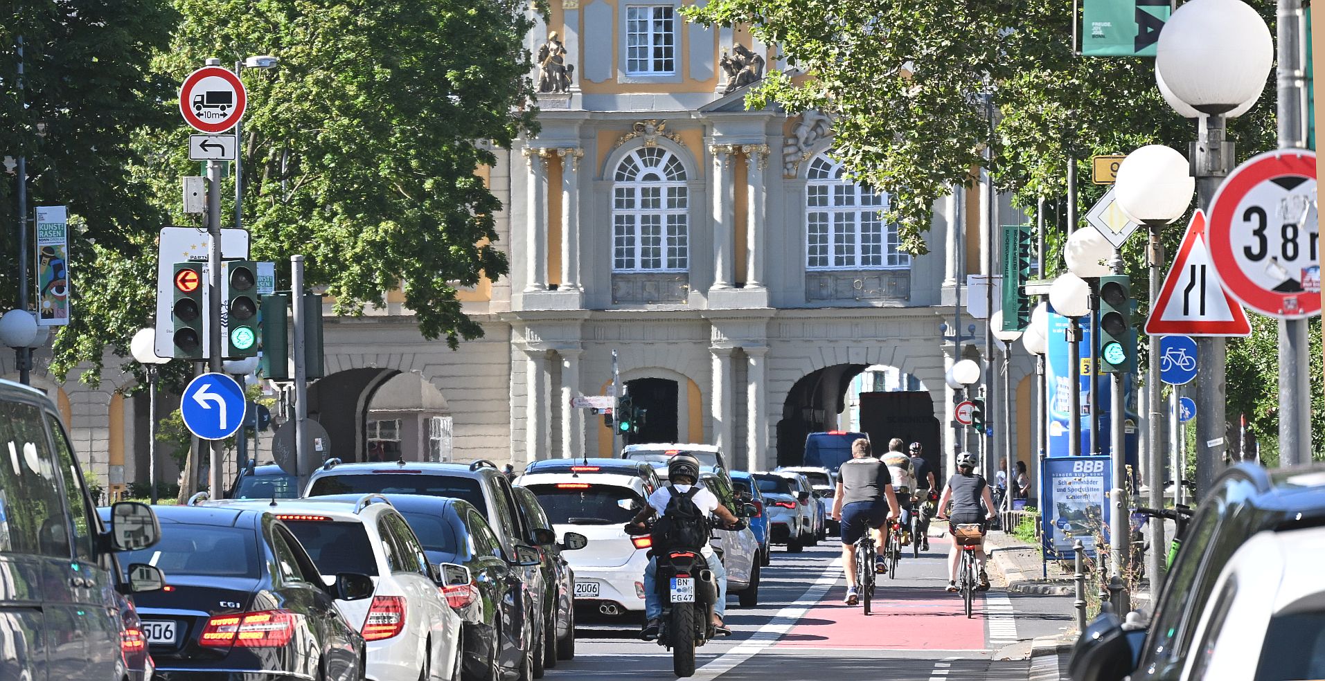 Koblenzer Tor mit Autoschlange in der Mitte und Radfahrenden am rechten, roten Fahrradstreifen
